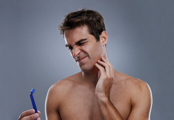 Man, shaving and beard or razor burn in studio for hair removal mistake, inflammation or grey background. Male person, tool and leaning or unhappy accident for wellness maintenance, pain or mockup