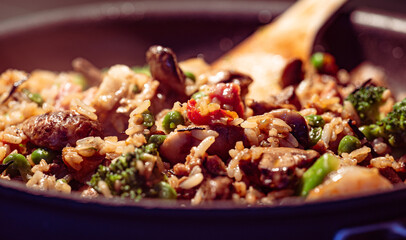 Close-up of a cooking pan featuring a freshly prepared dish of fried rice with mushrooms, green peas, and broccoli.