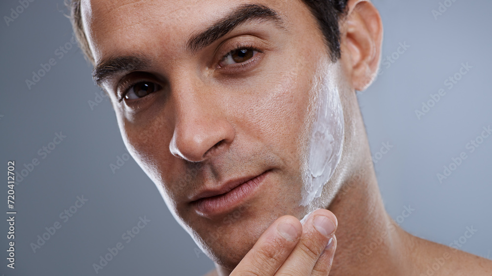 Wall mural Portrait, cream and man with dermatology, cosmetics and beauty on a grey studio background. Portrait, person and model with grooming routine or skincare with lotion or moisture after shave with shine