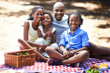 Portrait, happy and black family with forest picnic, fun or bonding in nature together. Love, food and children with parents in park for fruit, nutrition or healthy snacks while playing in the woods