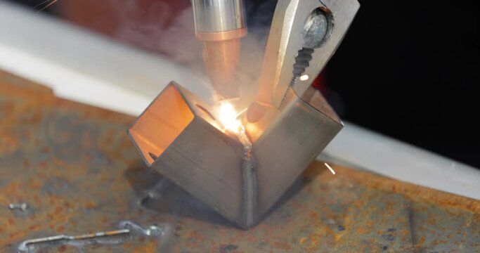 Laser welding machine with hand hold gun. Laser welding is shown in close-up.