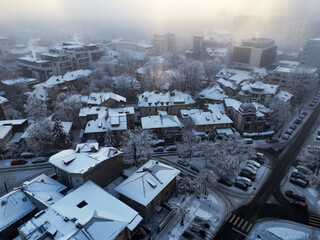 Aerial photography over Bucharest city. Fly over Bucharest City in winter season. Snowy day over blocks, streets and parking lot. Blizzard day in the city. Frozen block of flats in Bucharest. 