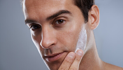 Portrait, cream and man with skincare, dermatology or wellness on grey studio background. Portrait,...