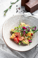 Fresh salad with quinoa, avocado, tomatoes, herbs and vegetables in a gray ceramic bowl on a concrete background. Dietary healthy dish for vegans, selective focus