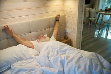 Obraz na płótnie Canvas Old man wakes up on a soft bed