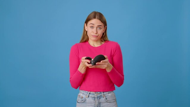 Sad woman throwing away empty wallet over blue background