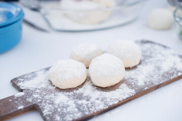 Close up of cook, chef rolling dough on small wooden board dusted with flour lying on white table. Concept of fast food.