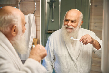 Old man doing his morning routine in the bathroom