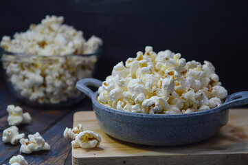 Popcorn in a small pan on a wooden background, selective focus.