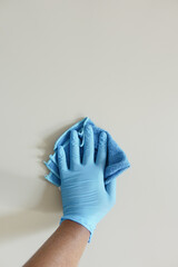 hand in blue rubber gloves cleaning table with cloth 