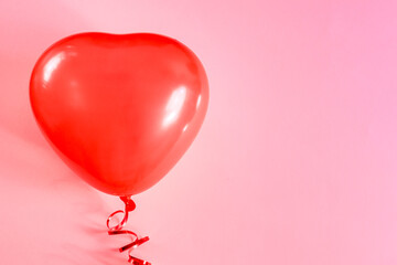 Red heart-shaped balloon on a pink background.