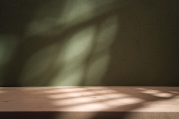 Empty table on khaki green texture wall background. Composition with monstera leaves shadow on the...