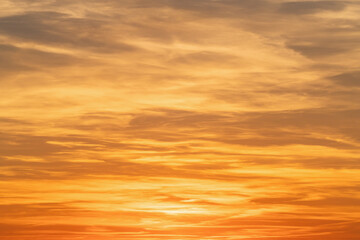 Sunset sky background with tiny clouds in orange and yellow colors.