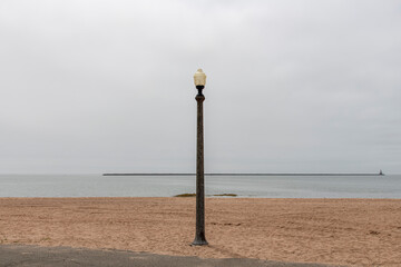 Panoramic view over beach of Lighthouse Point Park in New Haven, CT, USA with single streetlight and breakwater in distance with historic 1877 build Southwest Ledge Light at the end - obrazy, fototapety, plakaty