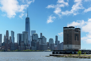 Panoramic view from waterfront in Jersey City, NJ, USA towards Lower Manhattan, New York City with skyline of skyscrapers on other side of Hudson river and Holland Tunnel Ventilation Shaft in front