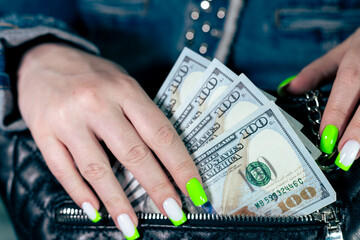 Woman takes out money from a stylish leather bag. A woman puts dollars into her bag
