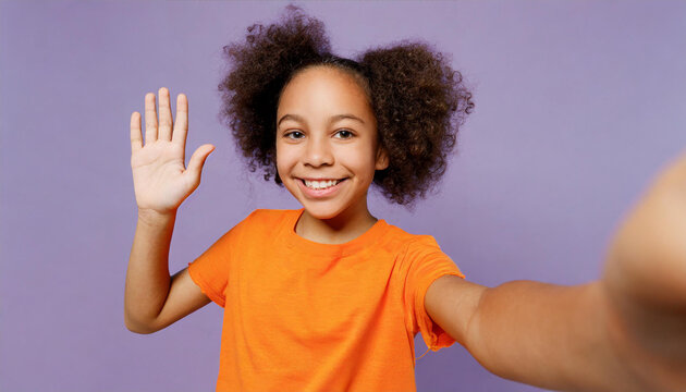 Close Up Little Kid Teen Girl Of African American Ethnicity Wear Orange T-shirt Do Selfie Shot Mobile Cell Phone Wave Hand Greet Isolated On Plain Pastel Purple Background Childhood Lifestyle Concept