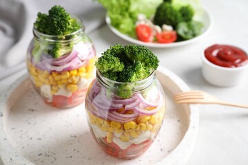 Healthy salad in glass jars on light table