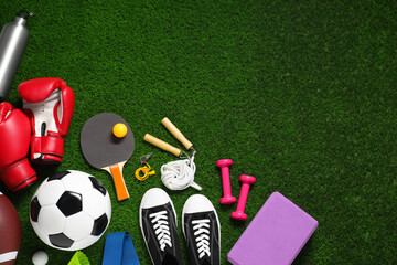 Different sports equipment on green grass, flat lay. Space for text
