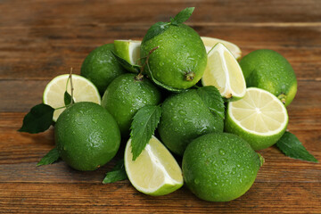Pile of fresh wet limes and leaves on wooden table