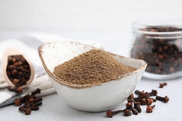 Aromatic clove powder and dried buds on light table, closeup