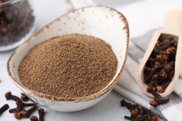 Aromatic clove powder and dried buds on light table, closeup