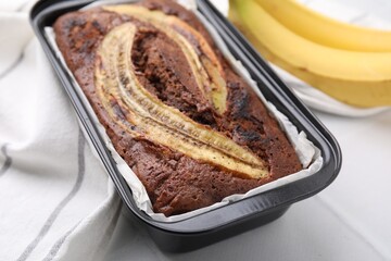 Delicious banana bread and fresh fruits on white tiled table, closeup