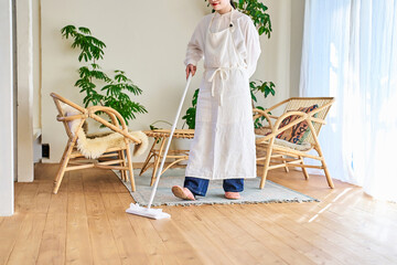 部屋のフローリングを掃除する若い女性