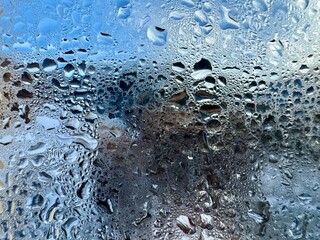 Condensation water drop on the window in winter with blur ice mountain on the background