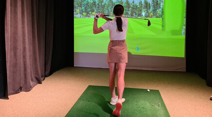 Professional female golfer holding club playing golf indoors on golf simulator concept