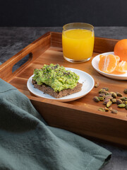 A healthy meal of avocado toast, orange juice, tangerines, and pistacios.