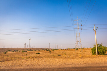 Wind turbines and transmission tower for renewable electric power production in India's second largest onshore wind farm of Jaisalmer windpark in Jaisalmer district of Rajasthan state.