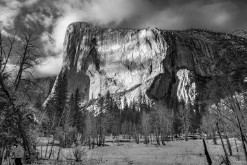 Dramatic black and white image of El Capitan mountain in Yosemite National park, California. With snow covered ground and misty skies