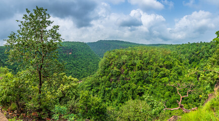 Fototapeta na wymiar Panoramic view of Pachmarhi valley having clouds shrouded hills of Satpura range rolling on each other from vantage point in Pachmarchi, Madhya Pradesh, India.