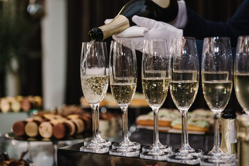 The waiter pouring white sparkling wine. Catering service concept. Barmen pours champagne into...