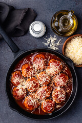 Beef meatballs with tomato sauce and parmesan cheese on gray background, close up