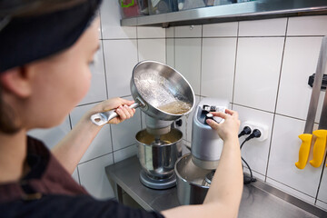 Qualified pastry chef adding confectionery ingredients to stand mixer