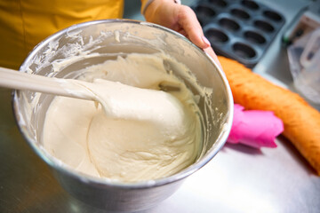 Female baker making dough for cupcakes on kitchen countertop