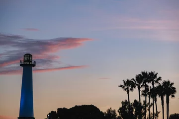 Fototapeten Silhouette of lighthouse and palm trees against beautiful sunset sunrise dusk dawn fire sky in Long Beach, California for romantic times © Tamme