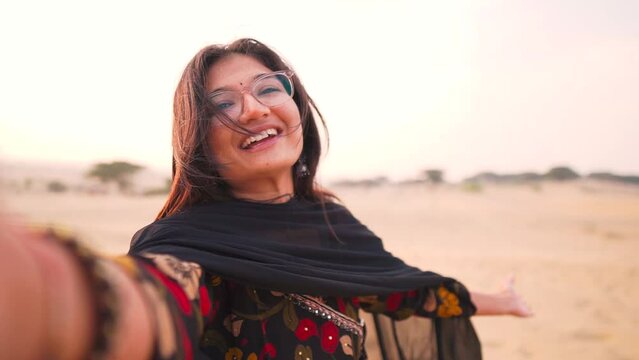 Selfie video of Indian girl vlogging in Thar desert at Jaisalmer, Rajasthan, India. Social media influencer recording her travel holiday in camera. Girl in Indian dress at Rajasthan desert. 