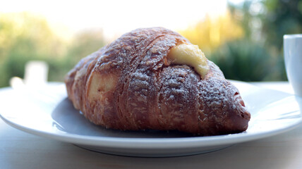 closeup of a croissant filled with cream, natural background, daylight