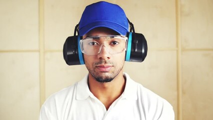 Construction, man and portrait with headphones for noise and protection glasses at work or site. Serious, person and handyman ready to start project with gear for sound and safety in industry