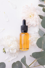 Pipette bottle with oil and flowers on white background, place for product, top view. Organic Serum Cosmetic nature for skincare