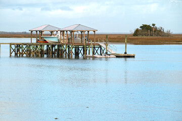 Pier and boat dock in a tidal estuary along the Atlantic Intercoastal Waterway, with a salt marsh...