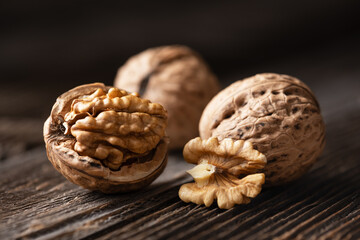 Whole and cracked walnuts with kernels on brown wooden plank close up. Food photography