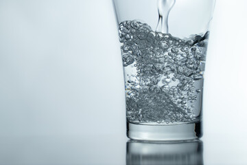 close-up Filling a glass with water showing a drink concept. bubbles in fresh water with white...