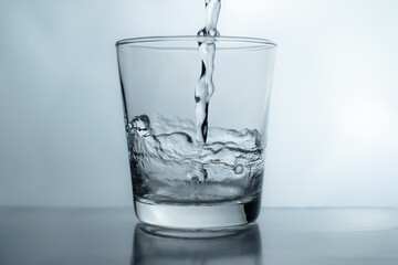 pouring water into glass on table, glass of water with splash isolated on white background. clean water for a good health. Mineral water in glass. 
