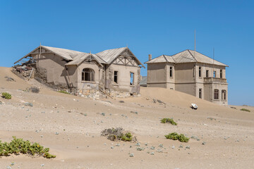 forsaken former "teacher" and "architect" buildings on sand at mining ghost town in desert, Kolmanskop,  Namibia
