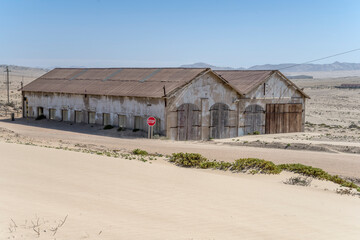 forsaken warehouse buildings on sand at mining ghost town in desert, Kolmanskop,  Namibia
