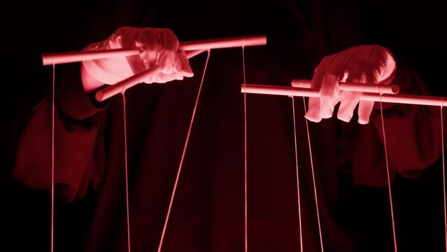 The puppeteer controls the puppets in the theater in red neon light close-up. Managing people at work, in politics and government. Action control